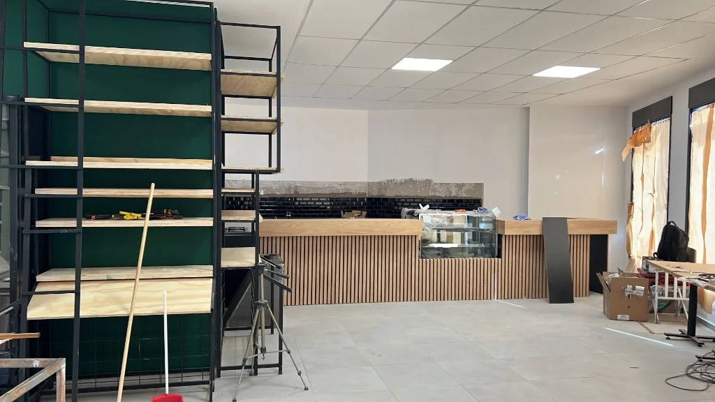 Proceso 2: Avance de obra en Arbo Café con montaje de barra de madera, estantería y revestimientos, por Surface Construcciones