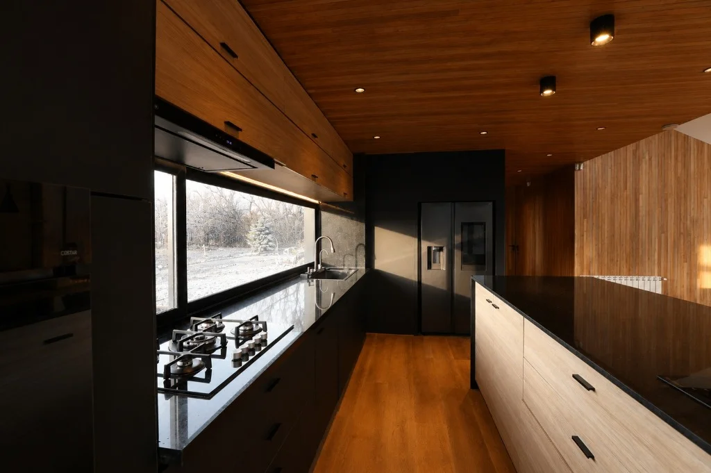 Surface Construcciones — Casa Nórdica (Trevelin, Patagonia), cocina moderna integrada con mesada en granito negro y cielorraso en madera