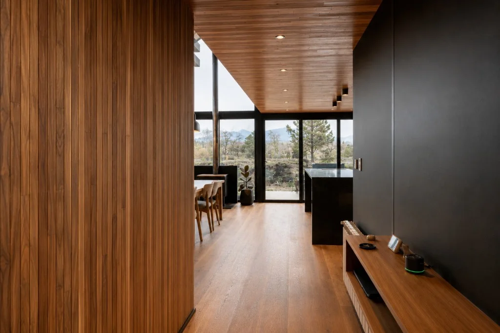 Surface Construcciones — Casa Nórdica (Trevelin, Patagonia), pasillo interior con alistonado vertical en madera y diseño de iluminación