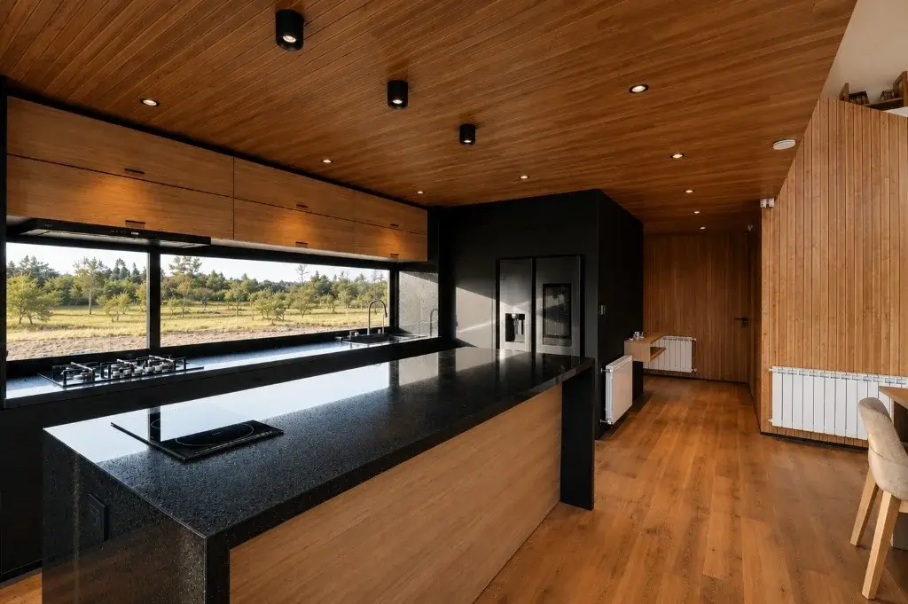 Surface Construcciones — Casa Nórdica (Trevelin, Patagonia), cocina con ventana panorámica horizontal hacia el parque