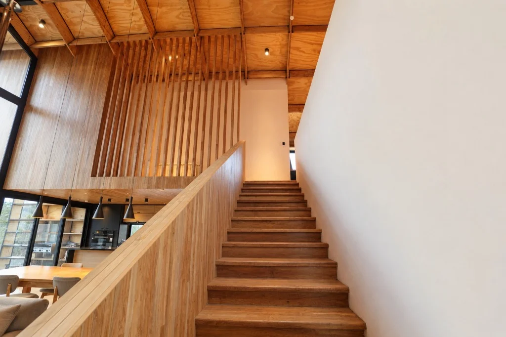Surface Construcciones — Casa Nórdica (Trevelin, Patagonia), vista de escalera en madera maciza conectando los niveles