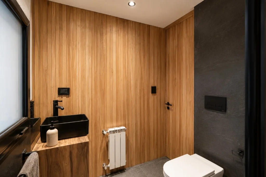 Surface Construcciones — Casa Nórdica (Trevelin, Patagonia), baño principal con bacha tipo batea negra y revestimientos cerámicos y de madera