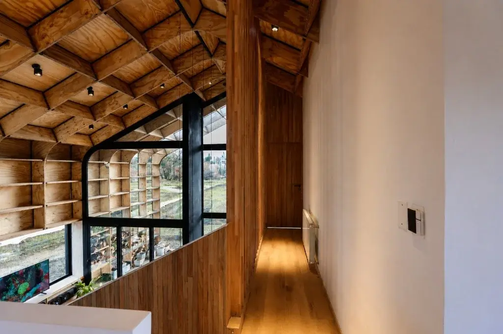 Surface Construcciones — Casa Nórdica (Trevelin, Patagonia), pasarela en planta alta sobre la doble altura y frente vidriado