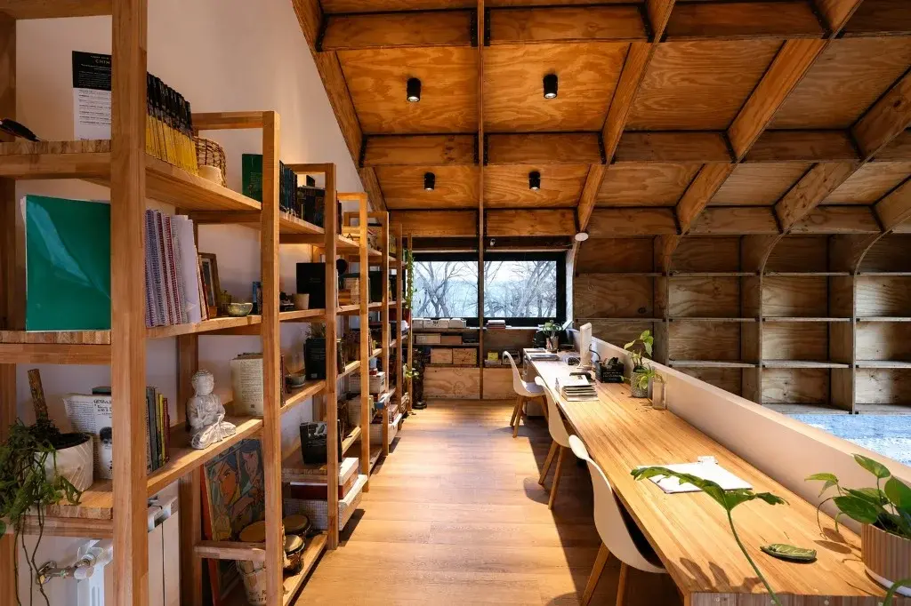 Surface Construcciones — Casa Nórdica (Trevelin, Patagonia), espacio de trabajo y biblioteca integrada bajo la cubierta curva de madera