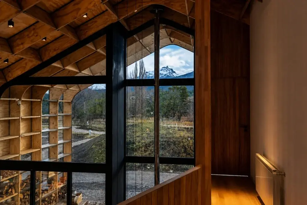 Surface Construcciones — Casa Nórdica (Trevelin, Patagonia), vista hacia la cordillera y picos nevados a través del ventanal gótico
