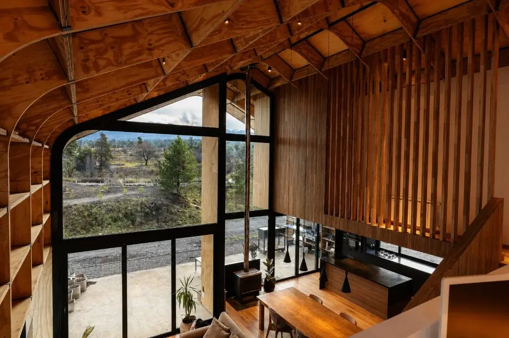 Surface Construcciones — Casa Nórdica (Trevelin, Patagonia), vista aérea interior de la doble altura, comedor e isla de cocina
