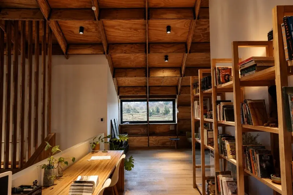 Surface Construcciones — Casa Nórdica (Trevelin, Patagonia), biblioteca de madera maciza y escritorio de lectura en planta alta
