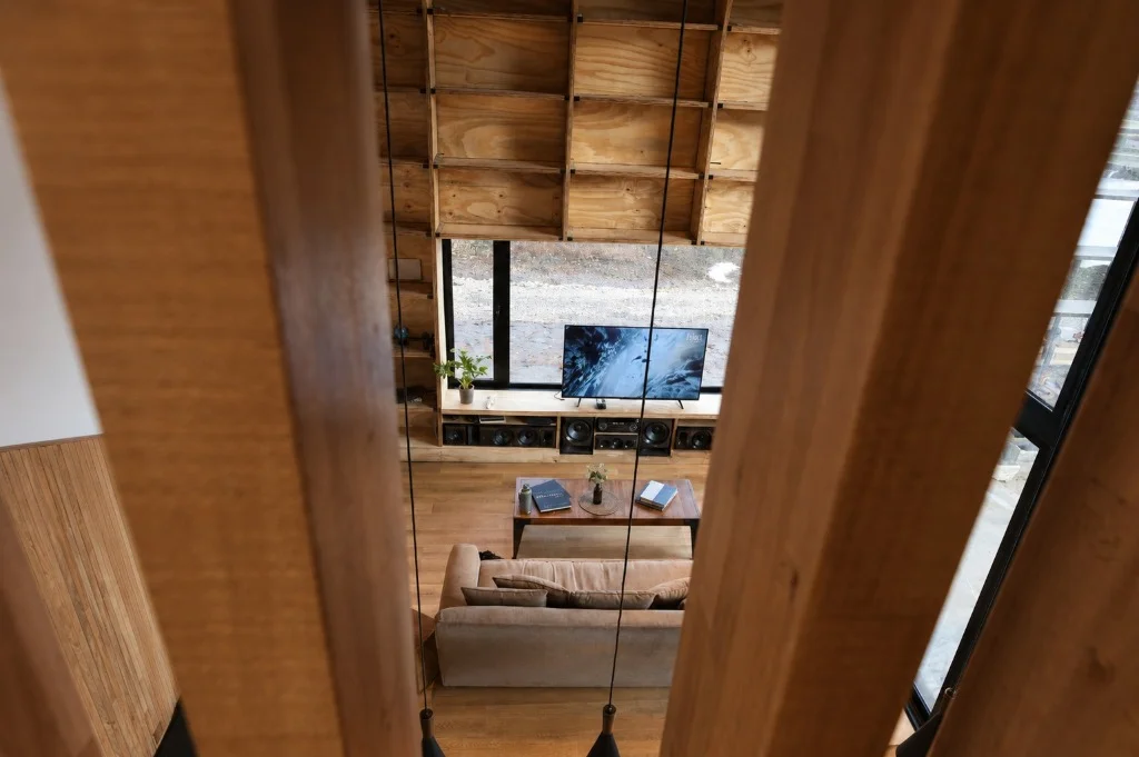 Surface Construcciones — Casa Nórdica (Trevelin, Patagonia), vista cenital del living desde el nivel superior entre divisores de madera
