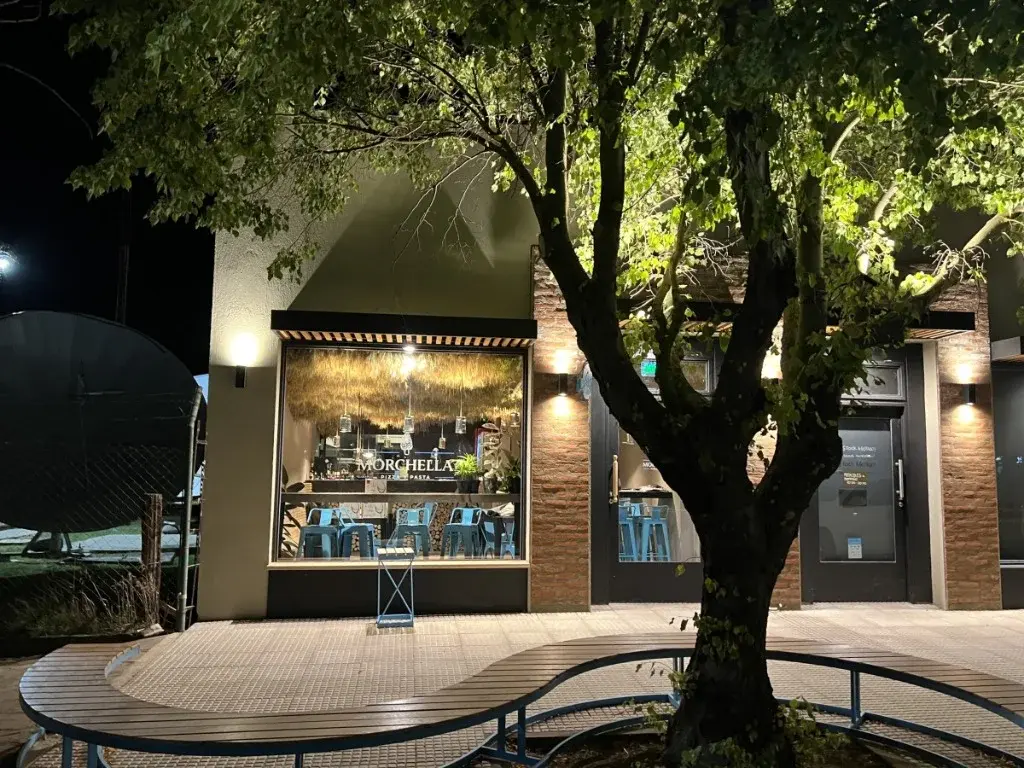 Surface Construcciones — Morchella, fachada exterior nocturna con frente comercial e iluminación