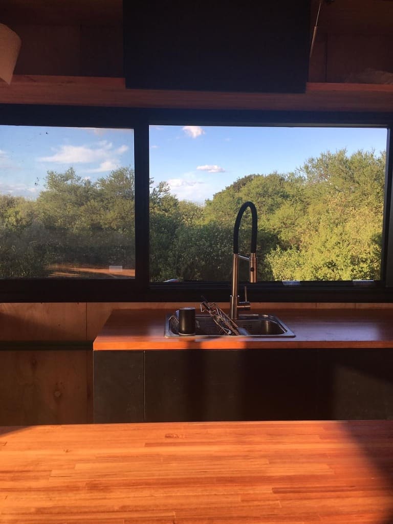 Surface Construcciones — Skate House (Trevelin, Patagonia), cocina terminada con ventanal al bosque